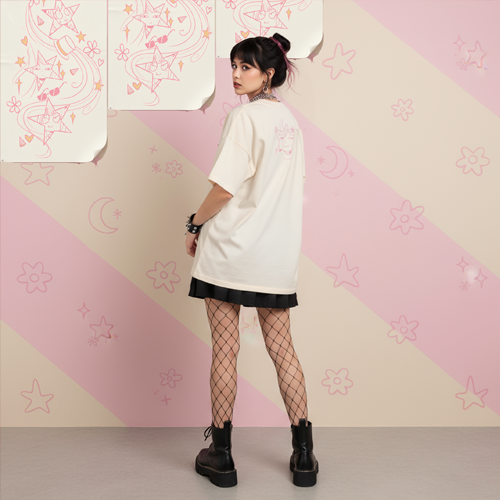 Девушка в бежевой футболке с аниме-принтом и чёрной юбке на фоне пастельных рисунков